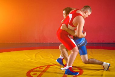 Wrestlng ve bir sarı halı spor salonunda güreş kıskaç yapıyor iki güçlü güreşçiler mavi ve Kırmızı tayt güreş vardır. 