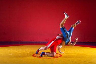 Mavi ve Kırmızı tayt güreş iki genç erkek wrestlng ve bir kalça bir sarı halı spor salonunda güreş yapmak vardır