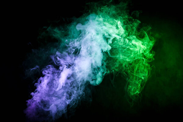 Dense multicolored smoke of blue,green on a black isolated background. Background of smoke vape