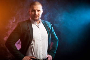 Genç yakışıklı işadamı adam beyaz gömlek ve gülümseyen ve kamera karşısında kırmızı ve mavi duman silmek--dan siyah izole özgeçmişlerine bakarak yeşil ceket