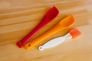 Ahşap bir masaya pişirme için güzel yeni lastik aksesuarları. Silikon spatula ve yemek için fırçalar