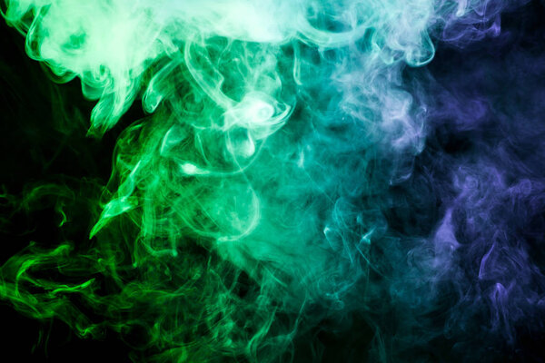 Colorful smoke of blue, green on a black isolated background. Background from the smoke of vape