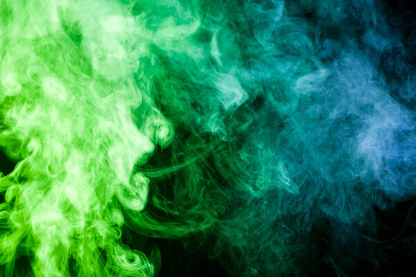 Colorful smoke of blue, green on a black isolated background. Background from the smoke of vape