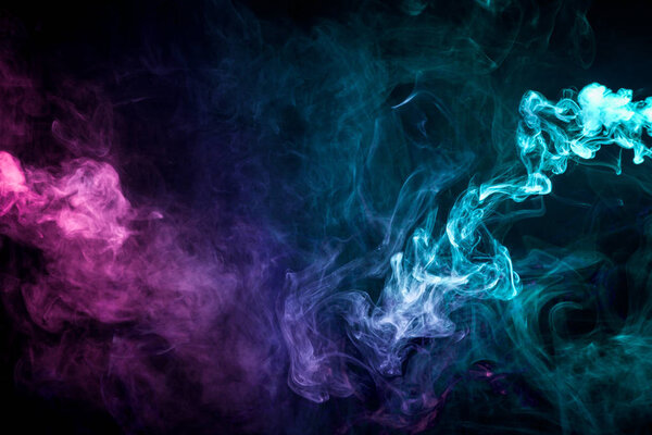 Thick colorful smoke of pink, green, blue on a black isolated background. Background from the smoke of vape