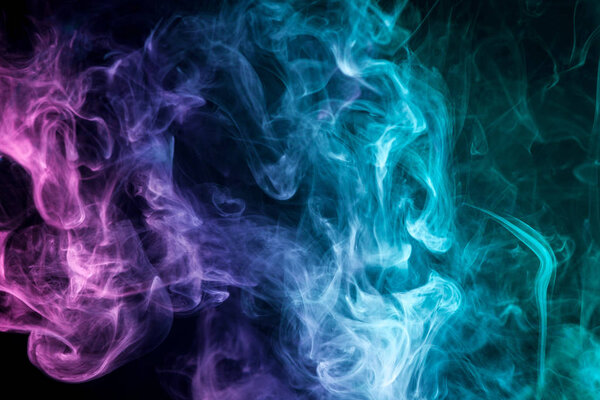 Thick colorful smoke of blue, purple on a black isolated background. Background from the smoke of vape