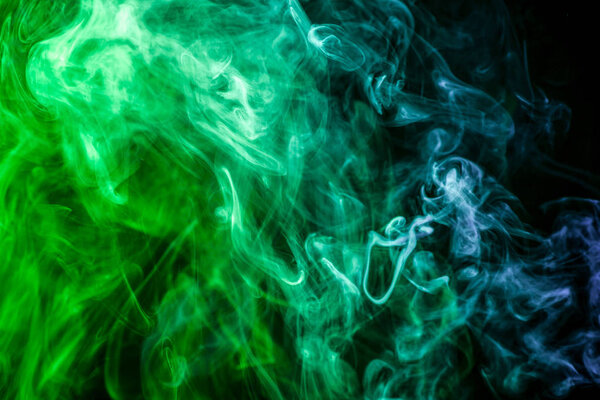 Dense multicolored smoke of blue and green colors on a black isolated background. Background of smoke vape