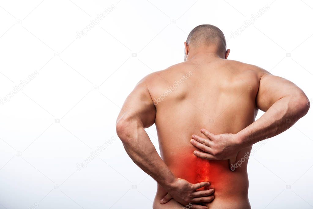 Injury of the spine. Young bald man sports physique holds a sick back on a white isolated background. Fracture of spine