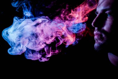 Genç bir adam izole bir siyah mavi ve pembe renk renkli duman bulutu exhales. Genç bir hırsız örneği içinde sigara içmek için zarar