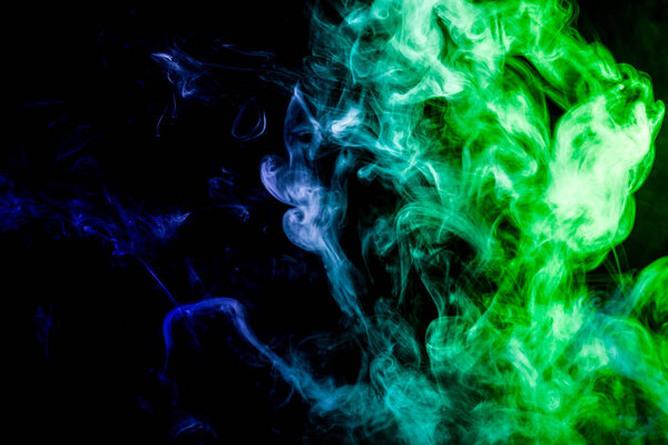 Thick colorful smoke of green and blue on a white isolated background. Background from the smoke of vape