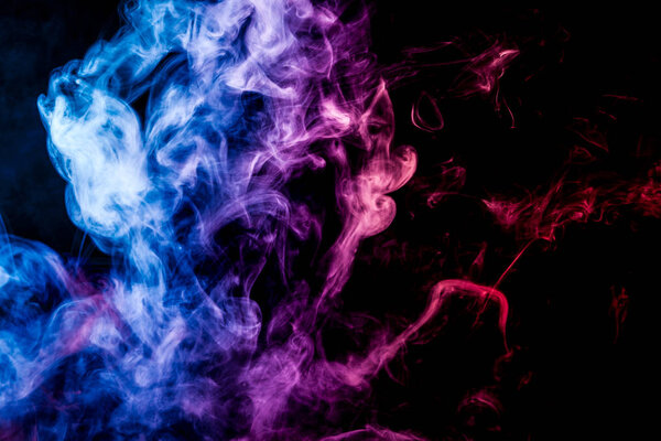 Thick colorful smoke of pink and blue on a black isolated background. Background from the smoke of vape