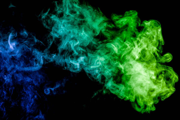 Colorful smoke of green and blue on a black isolated background. Background from the smoke of vape