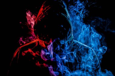 Siyah başlıklı genç bir adam sigara içiyor ve renkli mavi ve kırmızı vape siyah yalıtılmış zemin gelen duman dışarı nefes