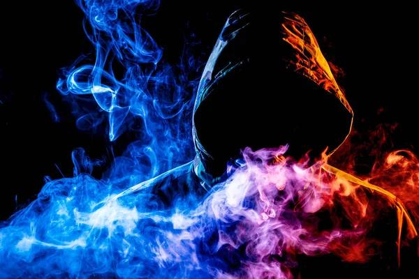 Siyah başlıklı bir genç adam bir vape dumanlar ve exhales renkli mavi, pembe, sarı siyah bir izole arka plan üzerinde duman
