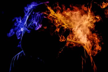 Siyah başlıklı bir genç adam bir vape dumanlar ve renkli turuncu ve mavi siyah bir izole arka plan üzerinde duman exhales
