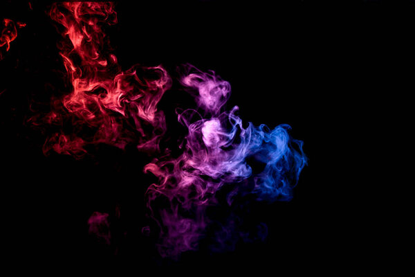 Dense multicolored smoke of blue, red, pink colors on a black isolated background. Background of smoke vape