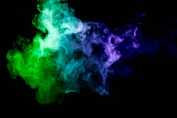 Dense multicolored smoke of blue, green colors on a black isolated background. Background of smoke vape