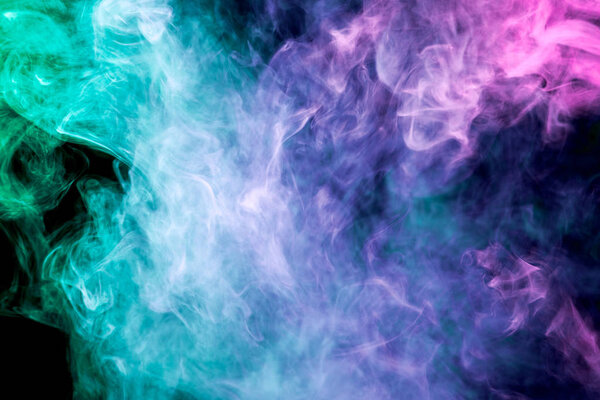 Dense multicolored smoke of blue, pink and purple colors on a black isolated background. Background of smoke vape