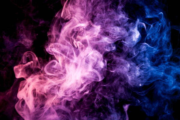 Dense multicolored smoke of blue, pink and purple colors on a black isolated background. Background of smoke vape
