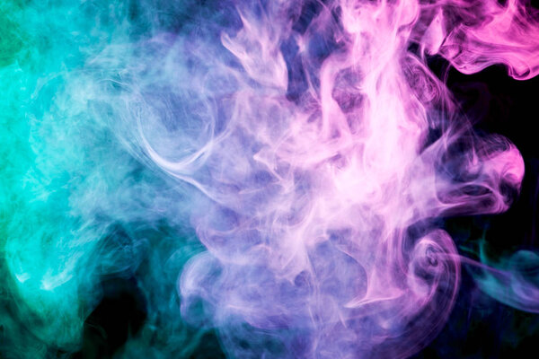 Thick colorful smoke of pink, blue, green on a black isolated background. Background from the smoke of vape