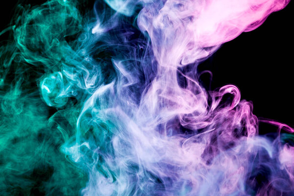 Thick colorful smoke of pink, blue, green on a black isolated background. Background from the smoke of vape