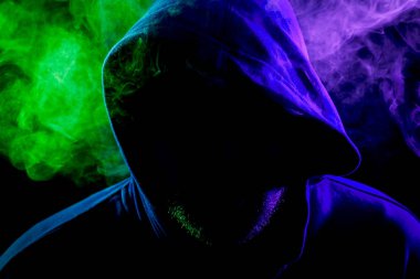 Genç bir adam bir siyah başlıklı bir renkli mor ve mavi siyah bir izole arka plan üzerinde duman çevresinde poz