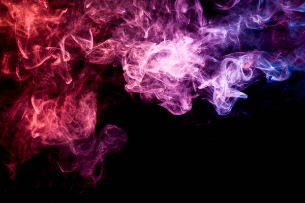 Thick colorful smoke of red, purple and blue on a black isolated background. Background from the smoke of vape