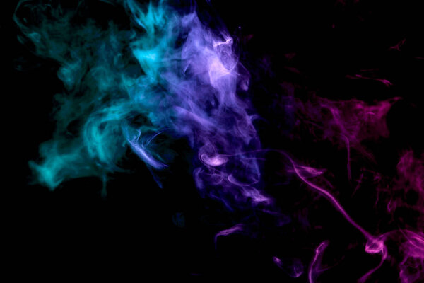 Thick colorful smoke of purple, blue and green on a black isolated background. Background from the smoke of vapee