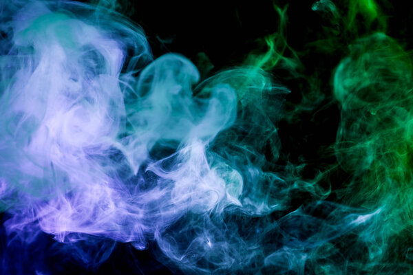 Thick colorful smoke of blue and green on a black isolated background. Background from the smoke of vapee