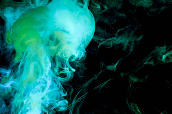 Dense multicolored smoke of blue and green colors on a black isolated background. Background of smoke vape