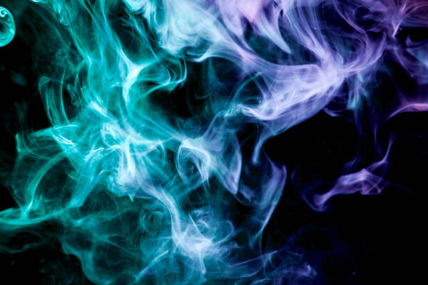 Dense multicolored smoke of blue and purple colors on a black isolated background. Background of smoke vape