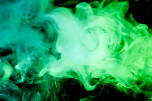 Colorful green smoke on a black isolated background. Background from the smoke of vape