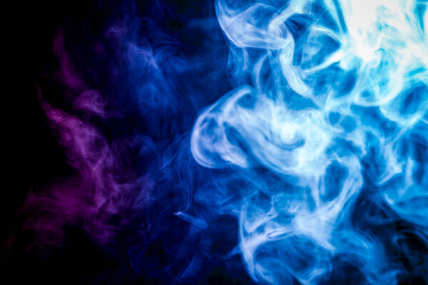 Dense multicolored smoke of blue and purple colors on a black isolated background. Background of smoke vape