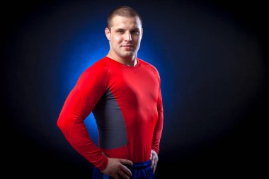 Güçlü bir esmer sportman karşı bir mavi bir ışık siyah yalıtılmış zemin poz bir kırmızı spor giyim rush Muhafız 