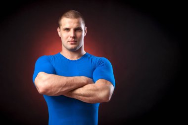 Güçlü bir esmer sportman mavi bir spor giyim rush Muhafız cidden kameraya bakar ve kollarını tutar kırmızı karşı göğsünde siyah yalıtılmış zemin ışıklar geçti 
