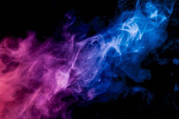 Dense multicolored smoke of blue, and pink colors on a black isolated background. Background of smoke vape