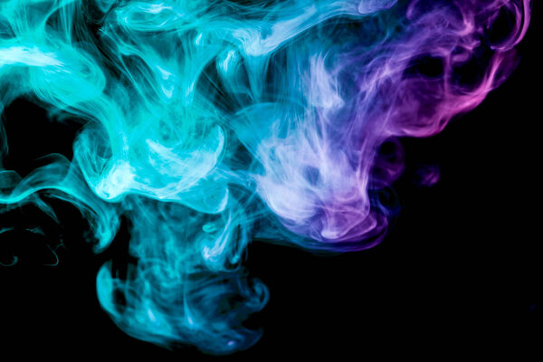 Thick blue, green and pink colorful smoke on a black isolated background. Background from the smoke of vape