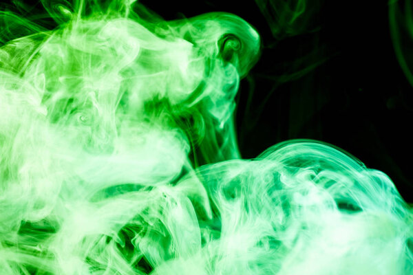 Dense multicolored smoke of green and yellow colors on a black isolated background. Background of smoke vape