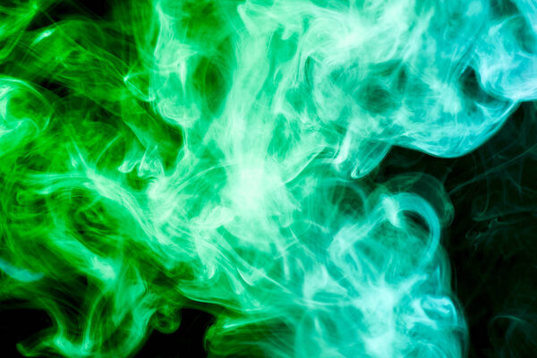 Dense multicolored smoke of green and yellow colors on a black isolated background. Background of smoke vape