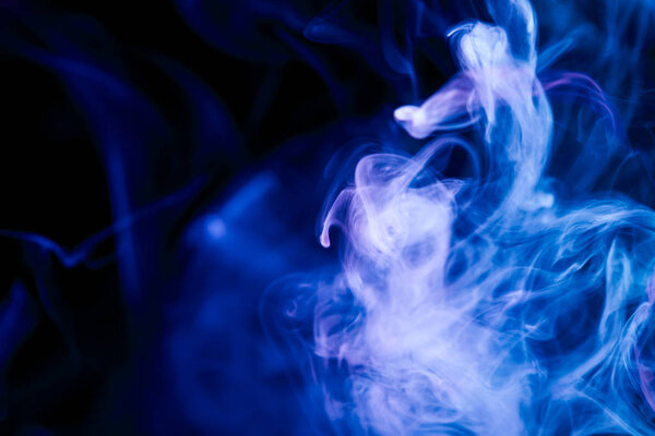 Dense blue and purple multicolored smoke on a black isolated background. Background of smoke vape