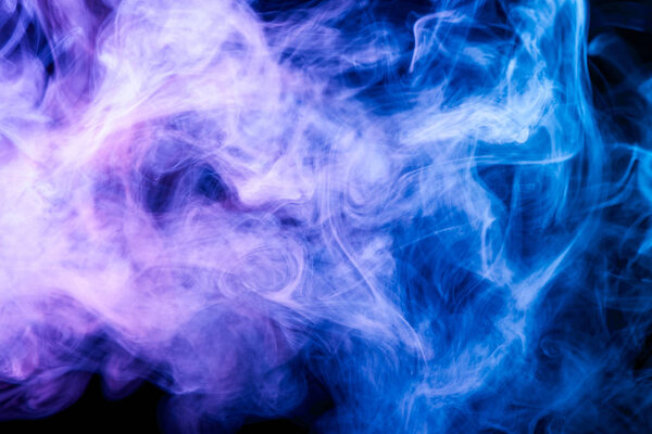 Thick colorful blue and purple smoke on a black isolated background. Background from the smoke of vape