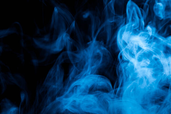 Thick colorful blue smoke on a black isolated background. Background from the smoke of vape