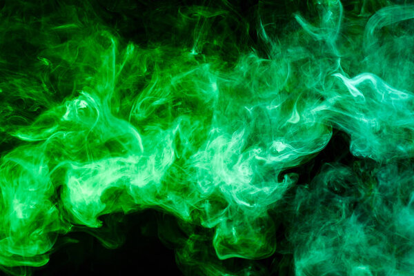 Dense multicolored green smoke on a black isolated background. Background of smoke vape