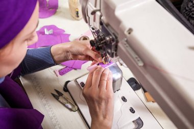 Mor bir unifrome bir terzi olarak çalışan genç bir kadın close-up bir dikiş makinesi, üstten görünüm hakiki deri çocuk ayakkabıları diker