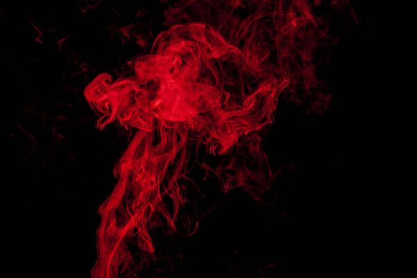 Thick colorful red smoke on a black isolated background. Background from the smoke of vape