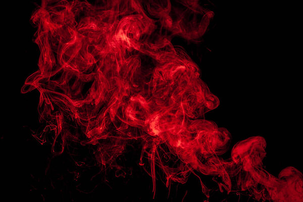 Thick colorful red smoke on a black isolated background. Background from the smoke of vape