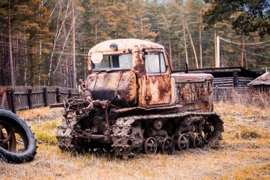 Kırık bir kapı ve bir yeşil iğne yapraklı orman arka tekerlekleri olmayan bir eski paslı traktör Close-Up