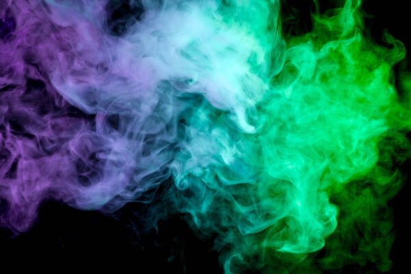 Colorful pink, green and blue smoke on a black isolated background. Background from the smoke of vap