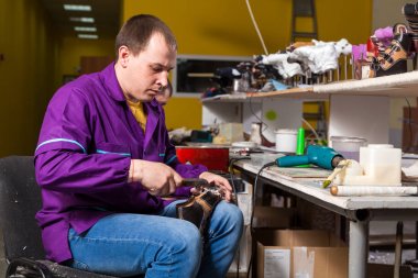 Bir genç adam işçi kot pantolon dikiş atölyede yapılan hakiki deri ile özel bir saç kurutma makinesi çocuk ayakkabı tabanı yapar