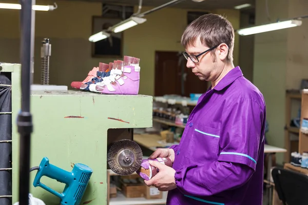 若い男性作業員は 本革の縫製工場で特殊な機械で作られた子供用の靴の底 — ストック写真
