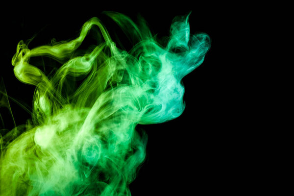 Thick green colorful smoke on a black isolated background. Background from the smoke of vap